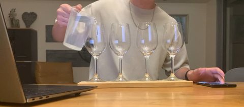 Wine glasses filled to different levels on a wooden table.