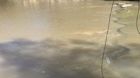 A hydrophone cable dropping into a river from the rocks, with the recorder beside it.